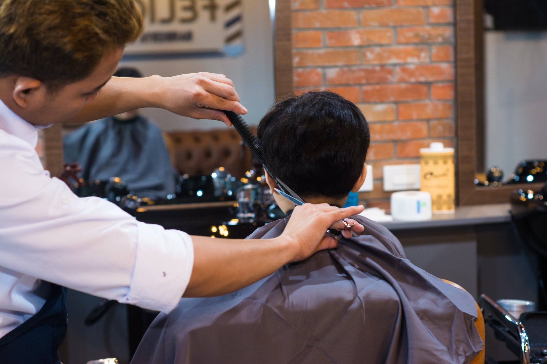 barber cutting client hair in saloon
